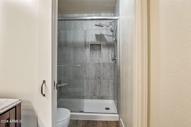 bathroom with vanity, hardwood / wood-style floors, toilet, and a shower with door