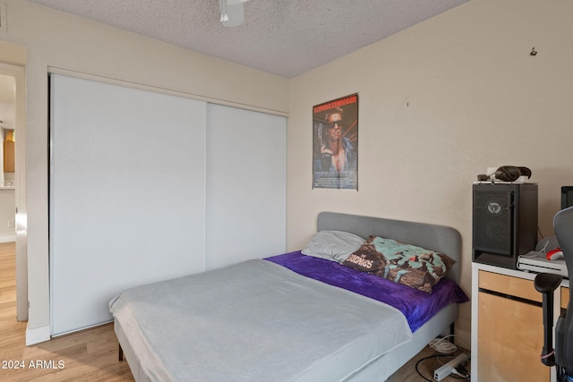 bedroom with a closet, a textured ceiling, and hardwood / wood-style floors