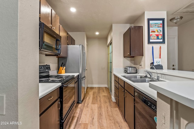 kitchen featuring black appliances, sink, and light wood-type flooring