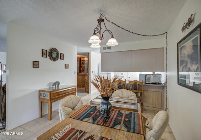 tiled dining space with a textured ceiling and a notable chandelier