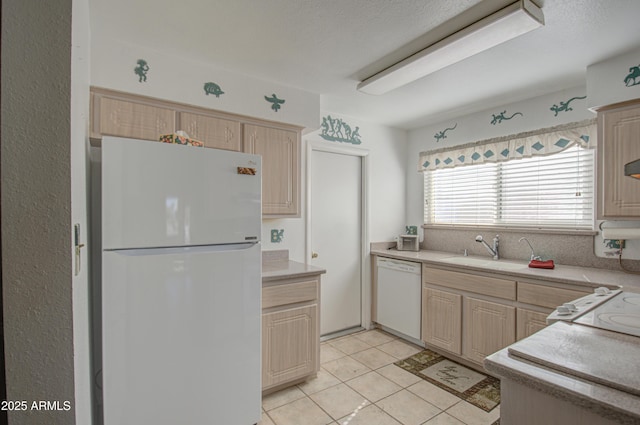 kitchen with sink, white appliances, light tile patterned floors, a textured ceiling, and light brown cabinets