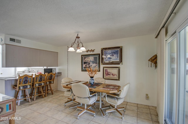 dining area featuring light tile patterned flooring, a chandelier, and a textured ceiling