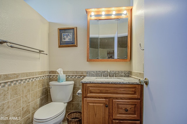 bathroom featuring tile walls, vanity, and toilet