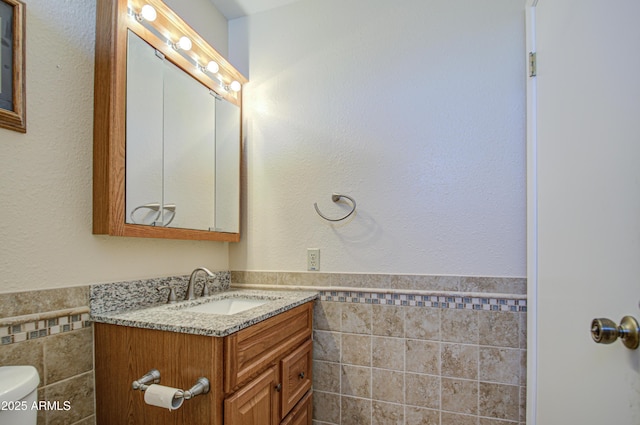 bathroom with tile walls, vanity, and toilet