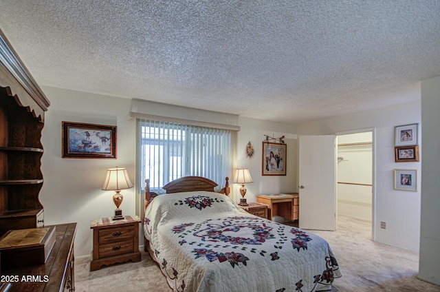 carpeted bedroom featuring a walk in closet and a textured ceiling