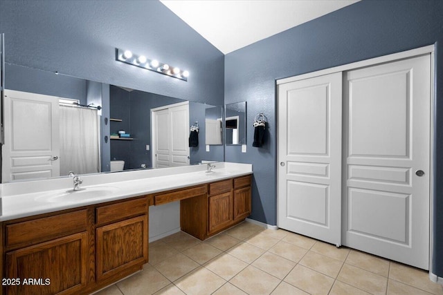 bathroom featuring double vanity, toilet, a sink, and tile patterned floors