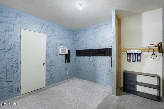 bathroom featuring a textured ceiling, concrete floors, and a wall unit AC