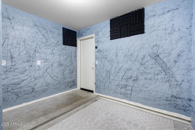 unfurnished room with a textured ceiling and baseboards