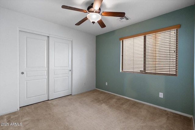 unfurnished bedroom with carpet floors, ceiling fan, visible vents, and a closet