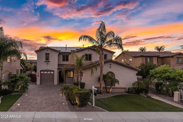 mediterranean / spanish house featuring a garage, a lawn, and solar panels