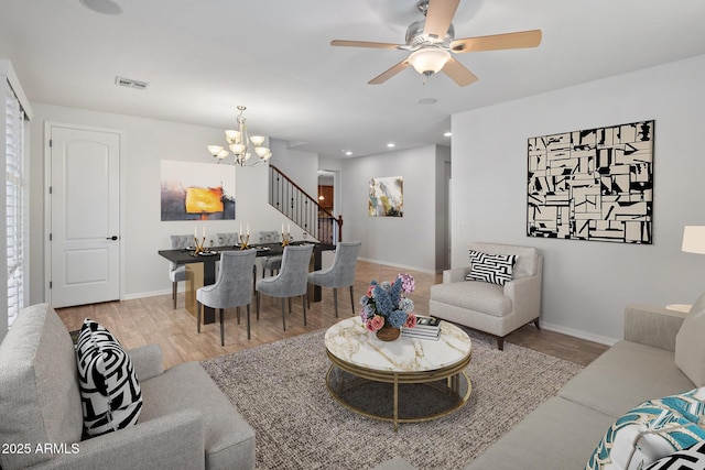 living room featuring light wood-type flooring and ceiling fan with notable chandelier