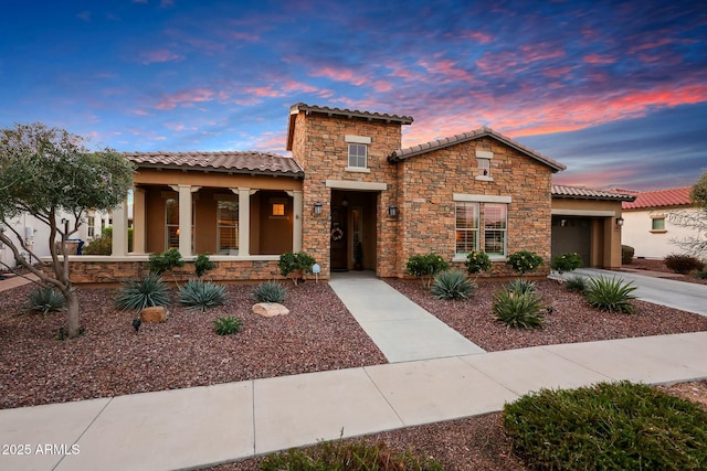 mediterranean / spanish-style house with a garage, concrete driveway, a tile roof, a porch, and stucco siding