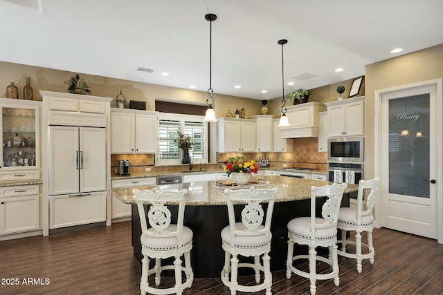 kitchen featuring a kitchen island, decorative backsplash, dark wood-type flooring, and built in appliances