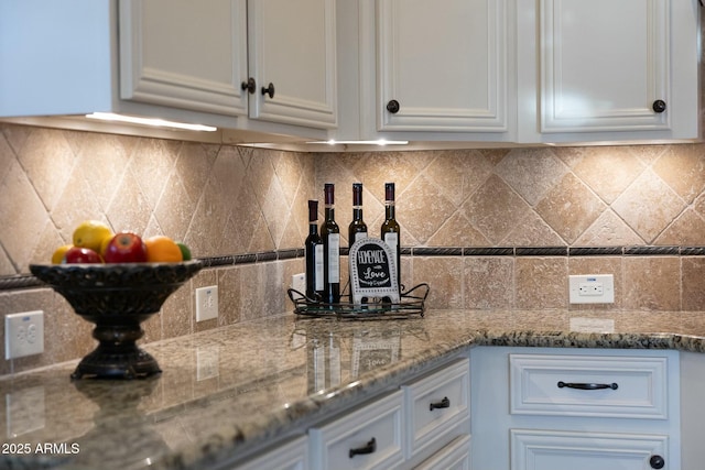 kitchen featuring stone counters, white cabinetry, and decorative backsplash