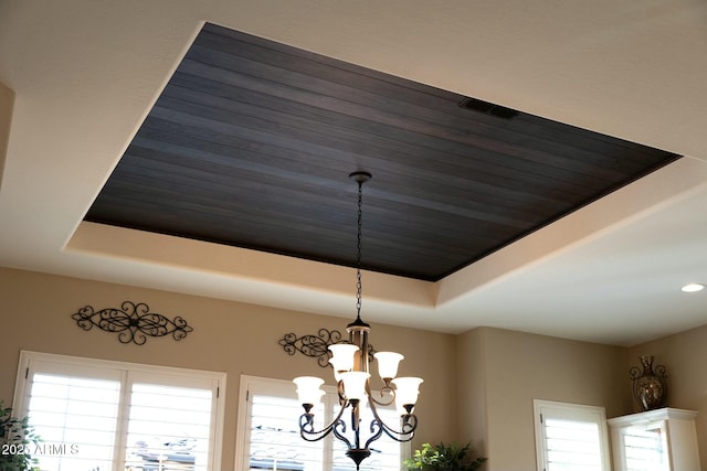 interior details with a tray ceiling and a notable chandelier