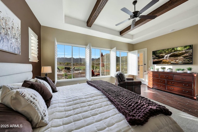 bedroom with beam ceiling, multiple windows, ceiling fan, and wood finished floors