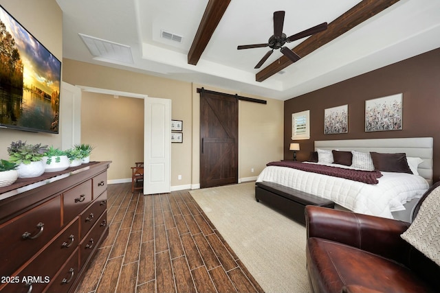 bedroom with a barn door, wood finish floors, visible vents, baseboards, and beamed ceiling