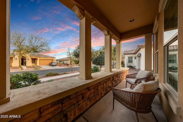 balcony at dusk featuring a porch