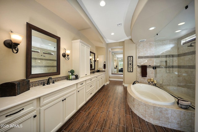 bathroom with a bath, wood tiled floor, walk in shower, and a sink