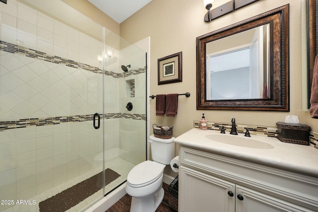 full bathroom featuring a stall shower, vanity, and toilet