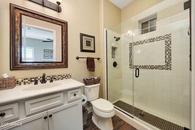 bathroom featuring a stall shower, tasteful backsplash, toilet, wood finished floors, and vanity