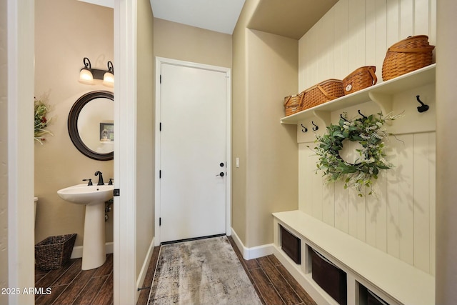 mudroom with wood finish floors, a sink, and baseboards