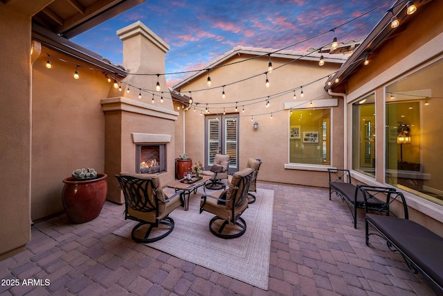 patio terrace at dusk featuring an outdoor living space with a fireplace