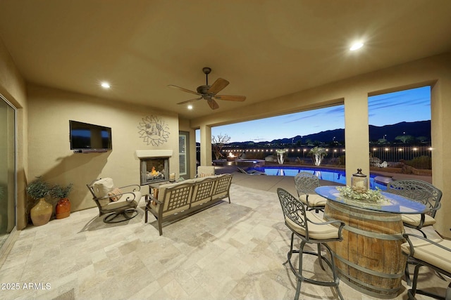 view of patio / terrace with an outdoor living space with a fireplace and ceiling fan