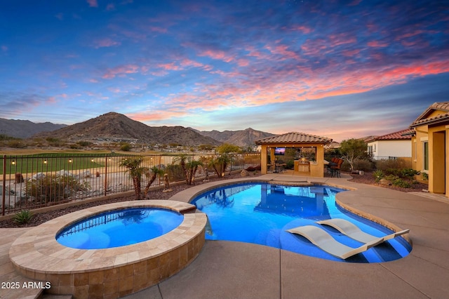 pool at dusk with a patio, a fenced backyard, a gazebo, a pool with connected hot tub, and a mountain view