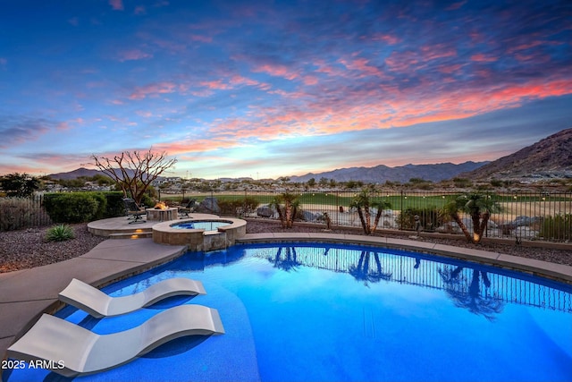 pool at dusk with fence, a mountain view, and a patio