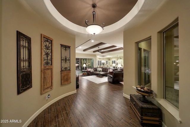 corridor featuring baseboards, a raised ceiling, wood finished floors, and recessed lighting