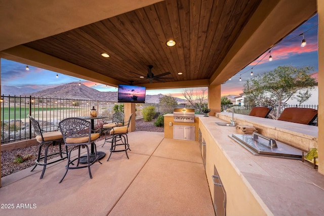 view of patio featuring grilling area, area for grilling, ceiling fan, a sink, and fence