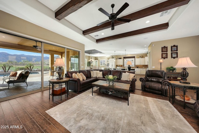 living room featuring beam ceiling, visible vents, dark wood-style flooring, and ceiling fan with notable chandelier