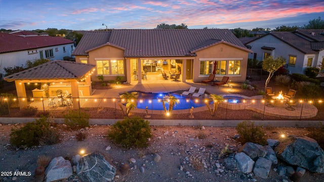 back of property at dusk with a patio, a fenced backyard, and a tiled roof