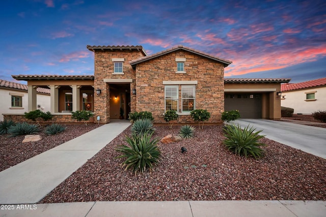 mediterranean / spanish-style house with driveway, an attached garage, and a tiled roof