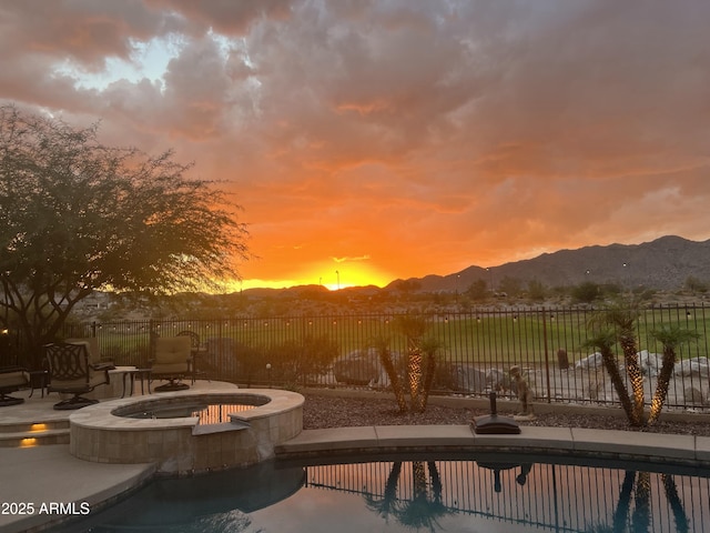 view of pool with a pool with connected hot tub, a patio, fence, and a mountain view