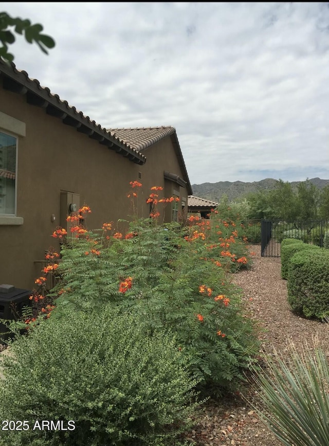 view of home's exterior featuring a mountain view, fence, a tiled roof, and stucco siding