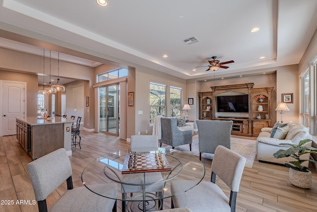 interior space featuring a raised ceiling, ceiling fan, and light wood-type flooring