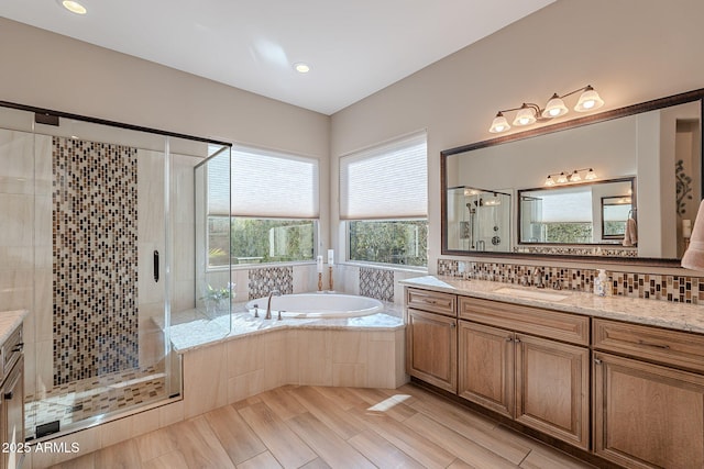 bathroom featuring vanity, shower with separate bathtub, and decorative backsplash