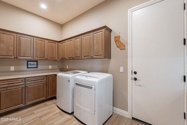 washroom with cabinets, washer and dryer, and light hardwood / wood-style flooring