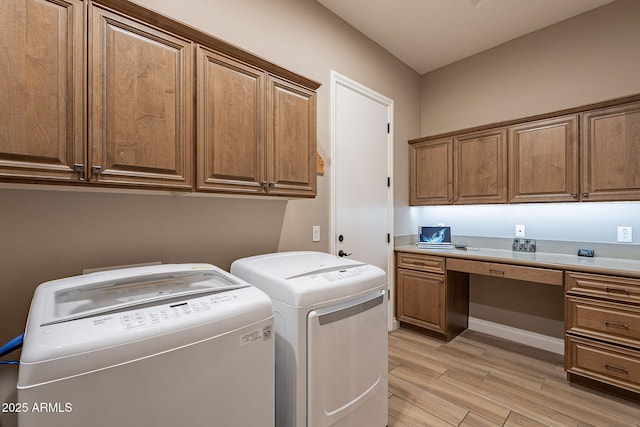 laundry area featuring independent washer and dryer, light hardwood / wood-style floors, and cabinets