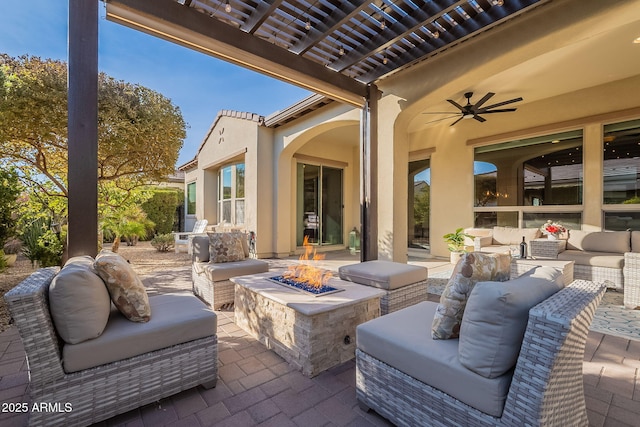 view of patio / terrace featuring ceiling fan and an outdoor living space with a fire pit