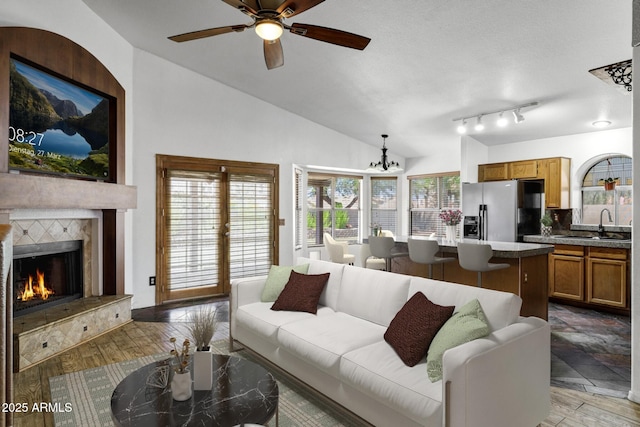 1245 W Cindy St, Chandler, AZ 85224 - living room with vaulted ceiling, a ceiling fan, a warm lit fireplace, and a chandelier