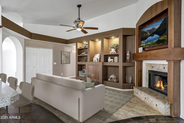 1245 W Cindy St, Chandler, AZ 85224 - living room featuring a high end fireplace, built in shelves, a ceiling fan, arched walkways, and wood finished floors