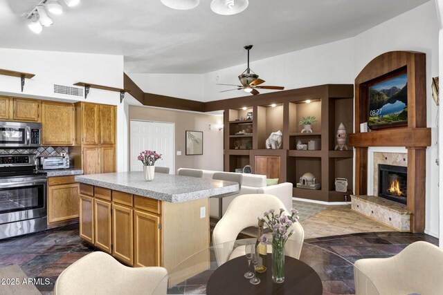 1245 W Cindy St, Chandler, AZ 85224 - kitchen with appliances with stainless steel finishes, lofted ceiling, light countertops, built in shelves, and a tiled fireplace