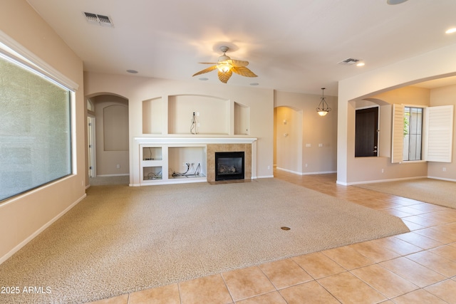 4241 E Andre Ave, Gilbert, AZ 85298 - unfurnished living room featuring light carpet, light tile patterned flooring, ceiling fan, arched walkways, and a tile fireplace