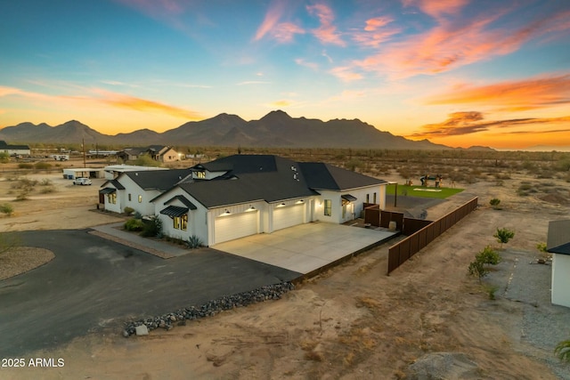 exterior space featuring a mountain view, concrete driveway, an attached garage, and fence