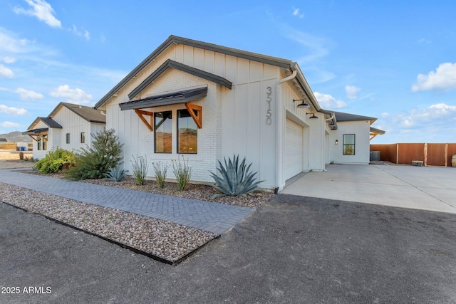 35150 N Bell Rd, Queen Creek, AZ 85144 - view of front of property with fence, board and batten siding, concrete driveway, an attached garage, and brick siding