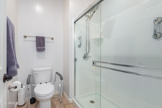 bathroom featuring tile patterned flooring, toilet, and a shower with shower door