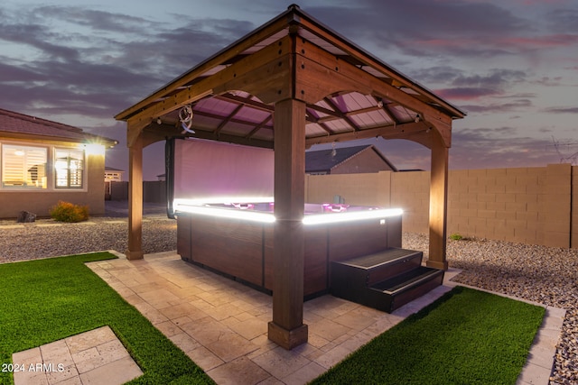 patio terrace at dusk featuring a gazebo and a hot tub